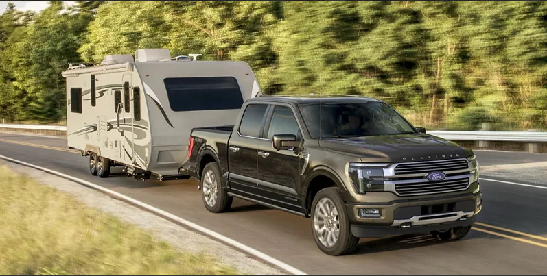 A black 2025 Ford F-150 towing a camper.
