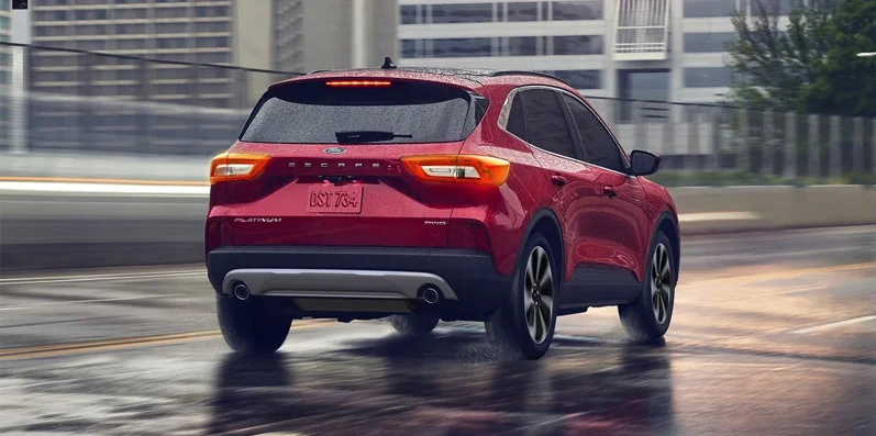 A red 2025 Ford Escape driving down a rainy road.