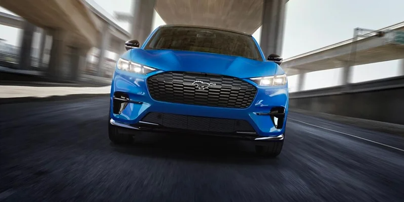 A blue 2025 Ford Mustang Mach-E driving toward the camera.